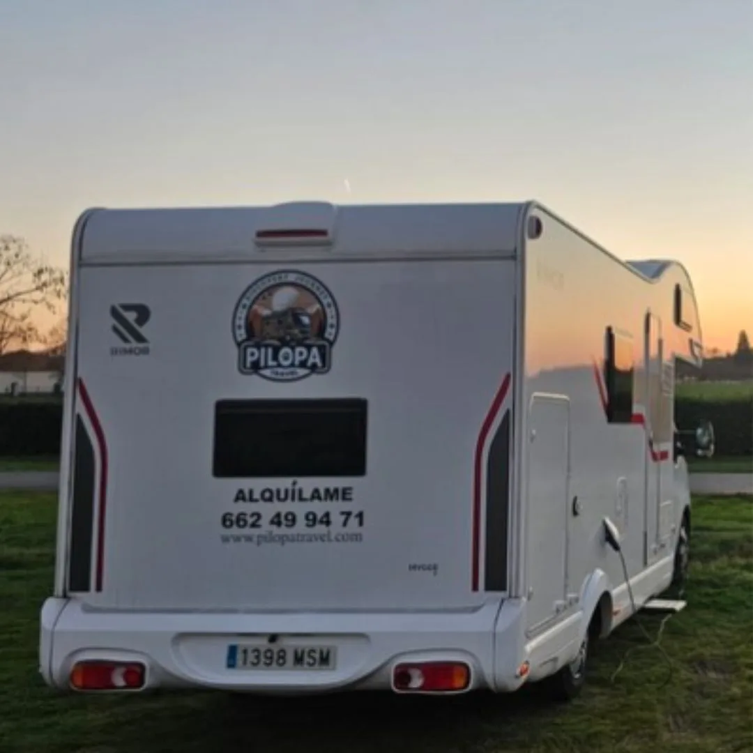 Vista trasera de la autocaravana aparcada en el campo durante la puesta de sol.