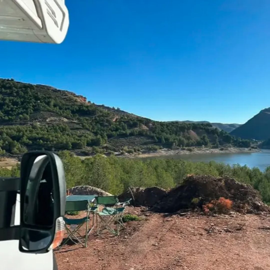 Paisaje de montaña y embalse visto desde el lateral de la autocaravana.